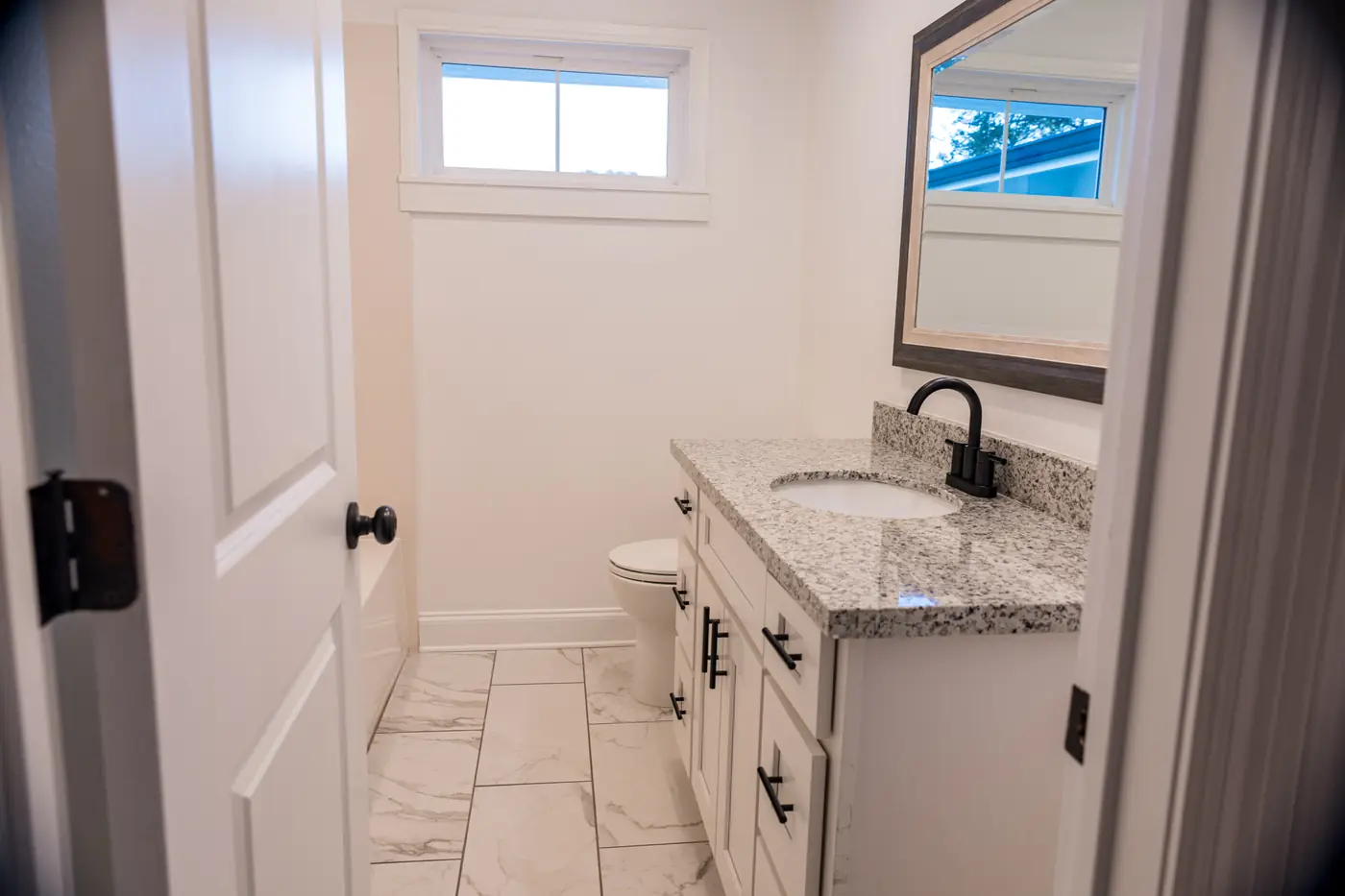 Vanity and tile floor Bathroom remodel with a granite-topped vanity, black hardware and marble-look floor tile in Metairie, LA