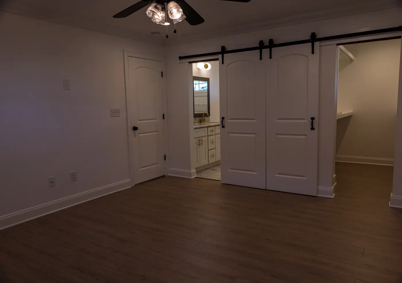 Bedroom with barn doors Bedroom remodel with sliding barn doors, wood-look flooring and a ceiling fan in Metairie, LA