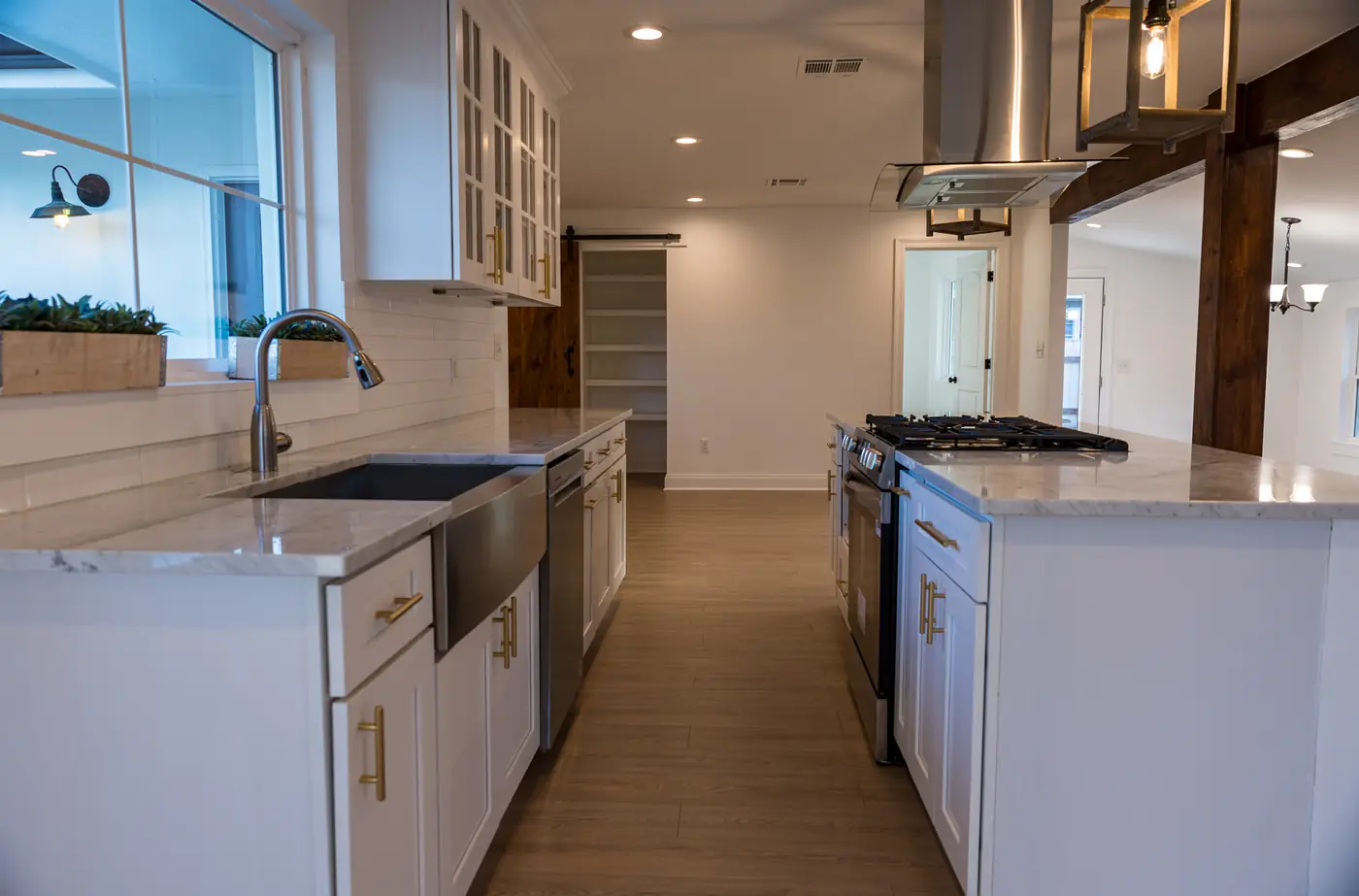 Farmhouse sink run Farmhouse sink under a window with white shaker cabinets and quartz counters in Metairie, LA