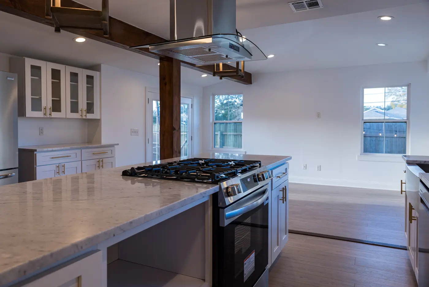 Island and gas range Kitchen island with a marble-look countertop facing a gas range and stainless hood in Metairie, LA