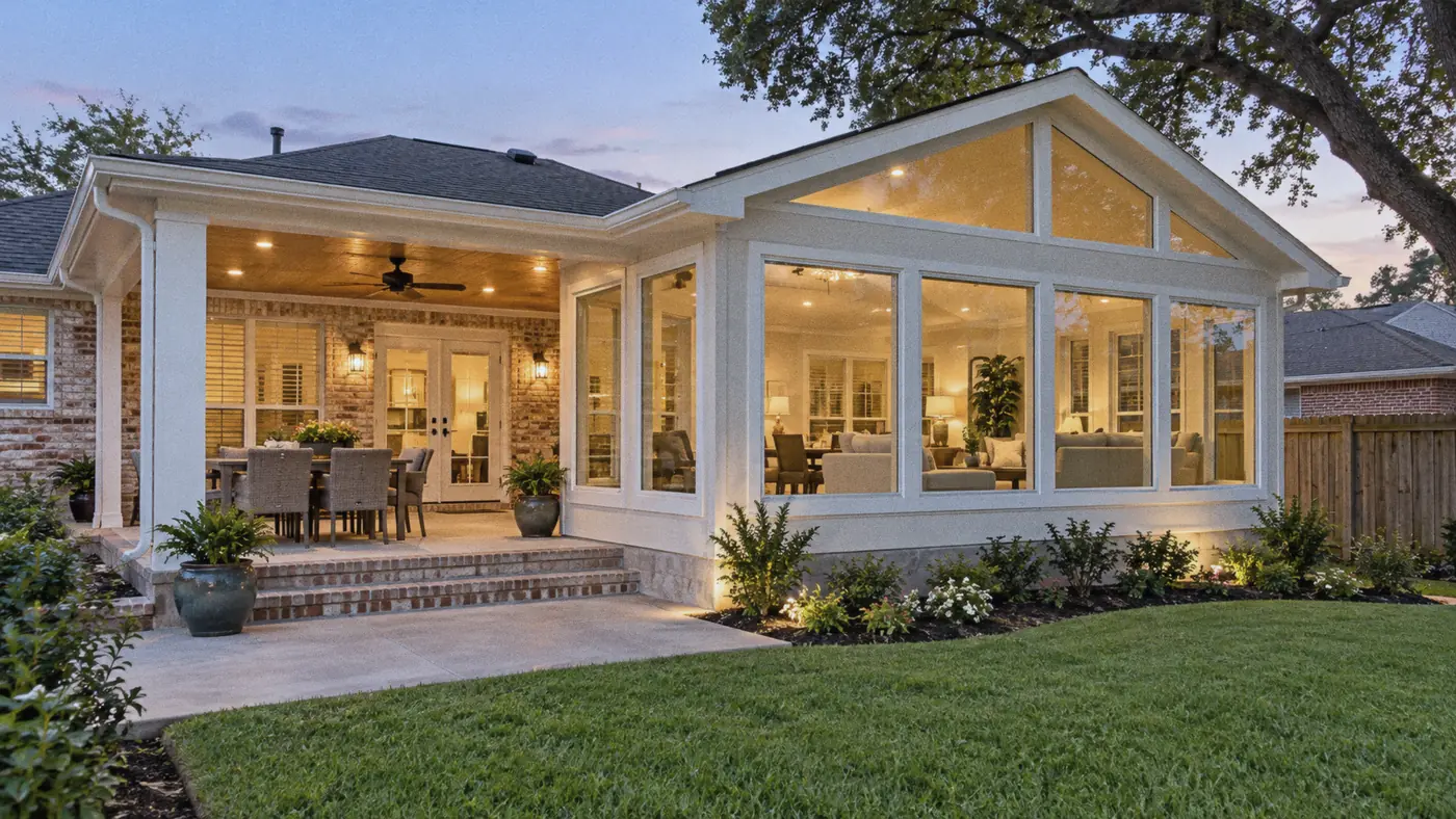 Concept rendering: backyard sunroom addition lit from inside at dusk with a stone step for Metairie, LA homes